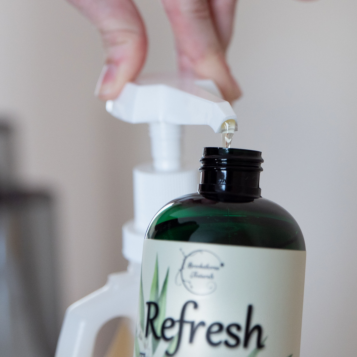 Refresh Massage Oil being pumped from a gallon jug into an 8oz bottle