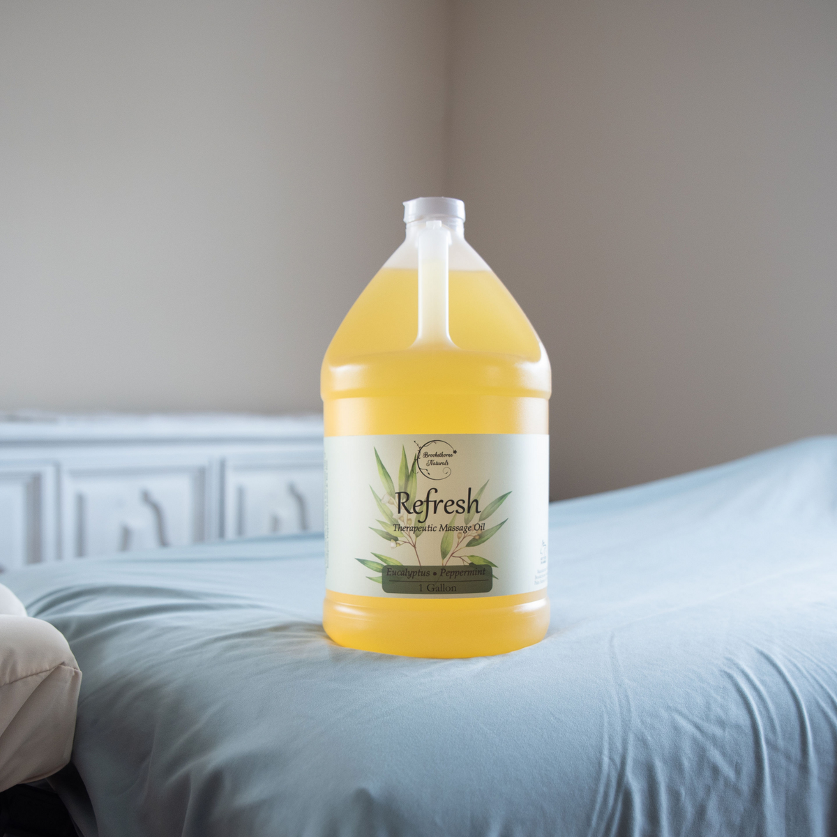 Refresh Therapeutic Massage Oil 1 Gallon jug sitting on a massage table