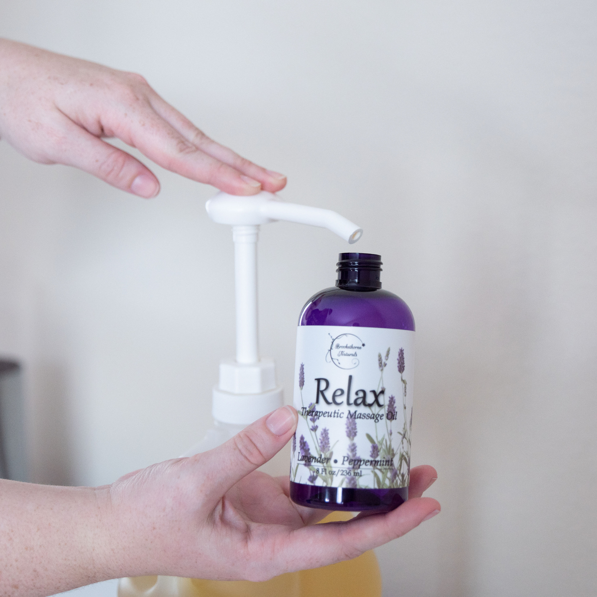 Relax Therapeutic Massage Oil being pumped from a gallon jug into an 8oz bottle