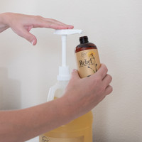 Relief Arnica Massage Oil being pumped from a gallon jug into an 8oz bottle