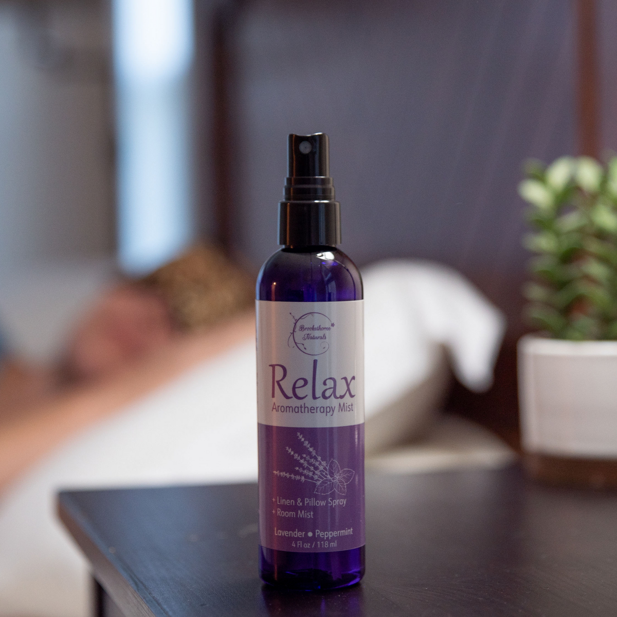 Relax Aromatherapy Mist on a nightstand with a person sleeping in the background