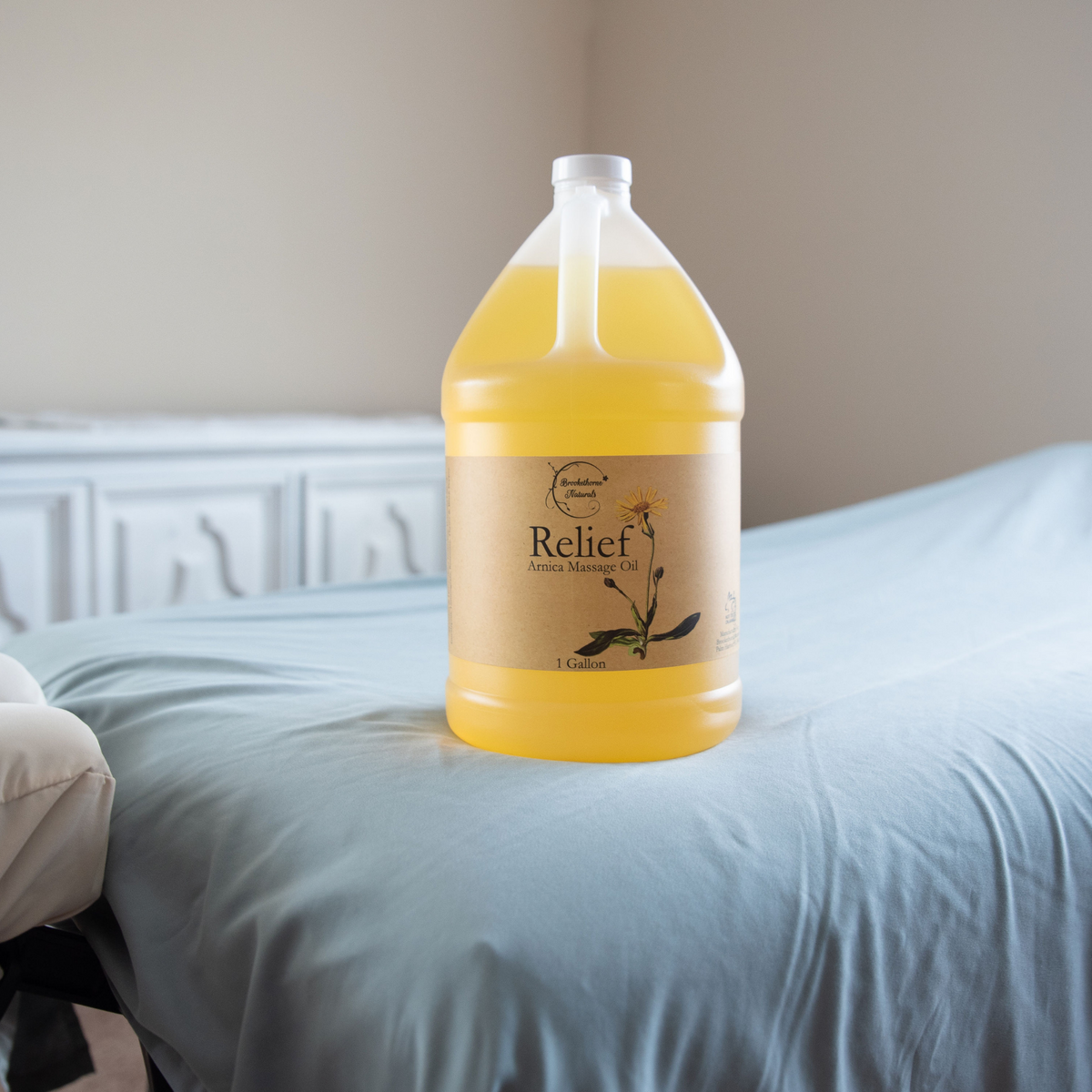 Relief Arnica Massage Oil Gallon Jug sitting on a massage table