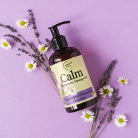 Calm Therapeutic Massage Oil on a purple background surrounded by lavender and chamomile flowers