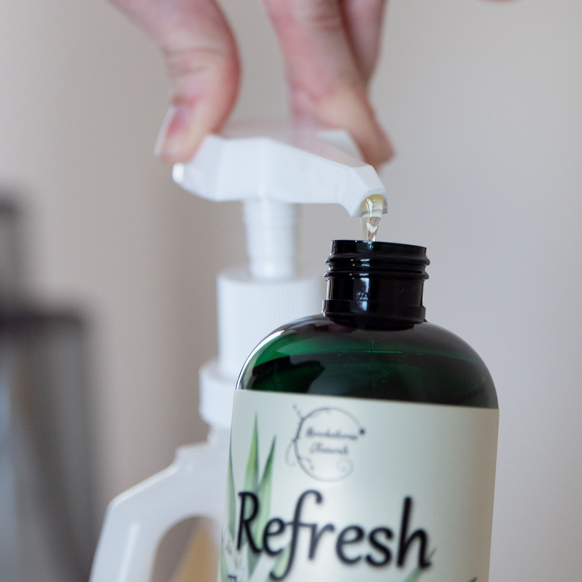 Refresh Massage Oil being pumped from a Gallon jug into an 8oz bottle