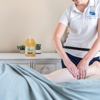A person is being massaged using the Refresh Massage Oil, the oil is showcased in the background