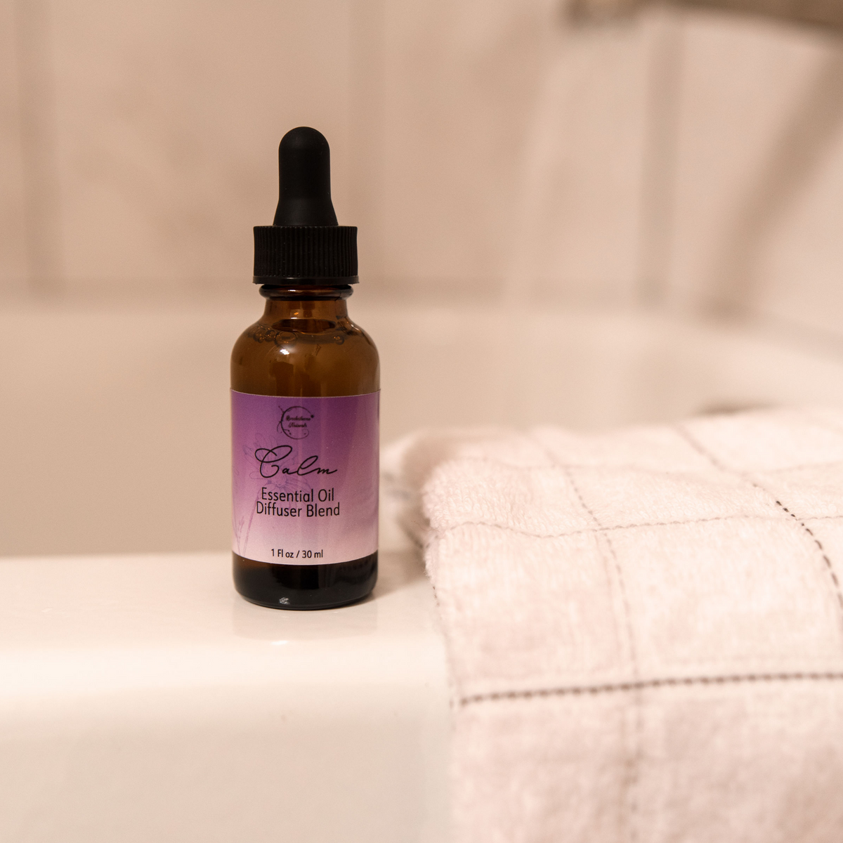 Calm essential oil diffuser blend sitting on a bath tub next to a bath towel