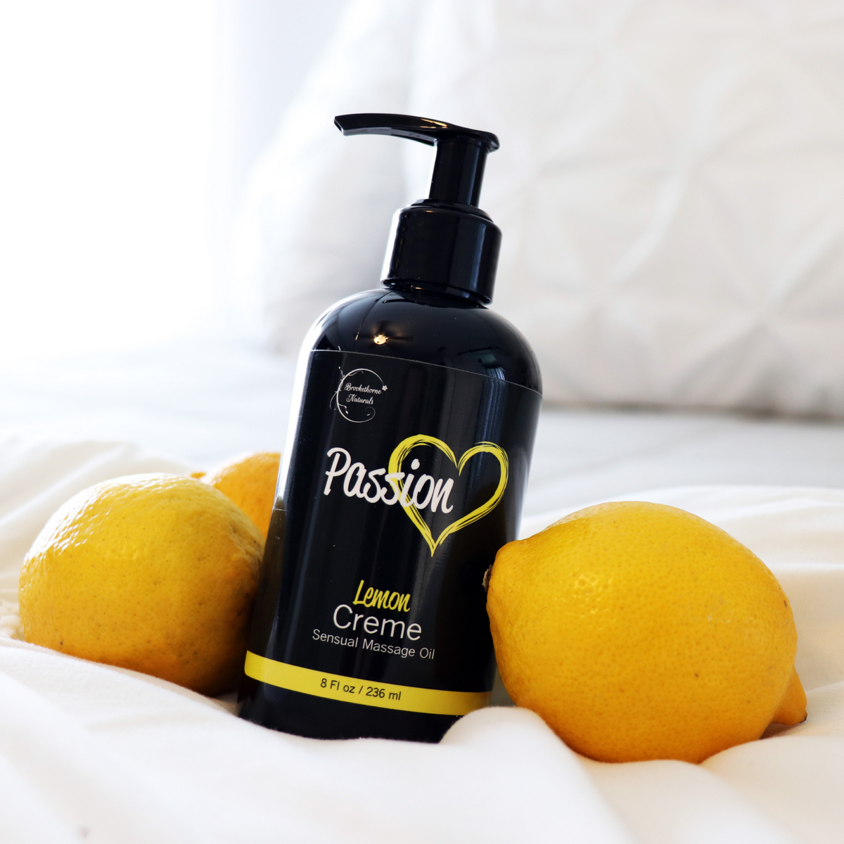 Picture of Passion Lemon Creme bottle on a bed next to lemons